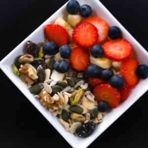 Bol grande de yogur con fresas, arándanos, nueces, semillas y frutos secos, presentado en un cuenco blanco