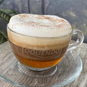 Taza de café con espuma y canela en polvo, sabor vainilla, servida en vaso de cristal