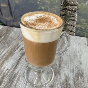 Bebida caliente Carolan’s con espuma y canela servida en taza de cristal