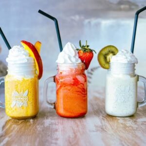 Vasos de frappé de fruta natural con nata decorados con fresa, melocotón y kiwi