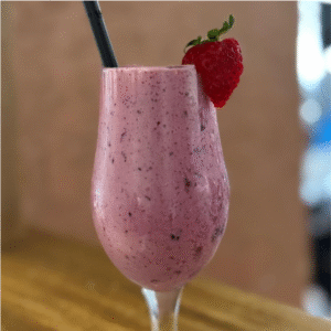 Batido de frutos rojos con fresa entera decorativa y pajita negra