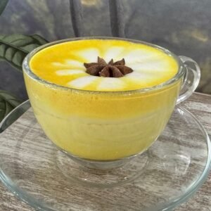 Taza de té leche dorada con cúrcuma, espuma decorativa y anís estrellado