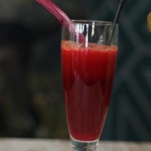 Zumo natural de manzana, zanahoria y remolacha servido en vaso alto con pajita