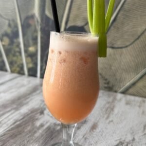 Zumo natural de piña, pomelo y apio servido en copa con tallo de apio decorativo