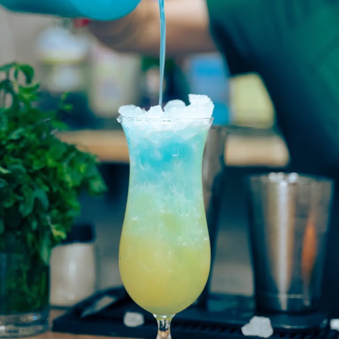 Bebida azul "Pitufo" servida en copa alta con hielo y toques tropicales