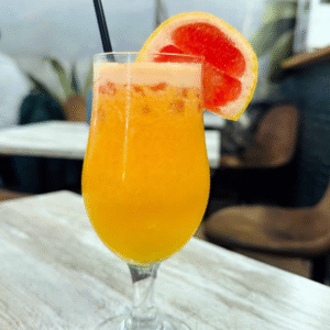 Zumo natural de pomelo, naranja y cúrcuma servido en vaso alto con rodaja de pomelo