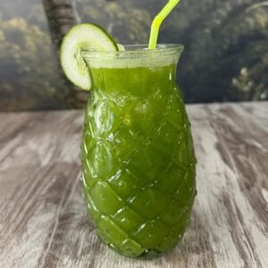 Jugo verde natural en vaso de piña con rodaja de pepino y pajita