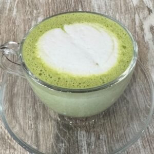 Taza de té matcha con leche y arte latte sobre mesa de madera