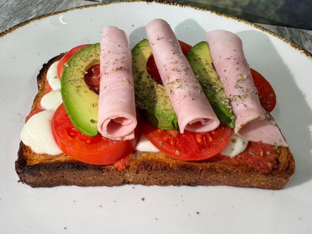 Tostada Tentación Italiana con aguacate, mozzarella, tomate y jamón cocido sobre pan de tomate y orégano